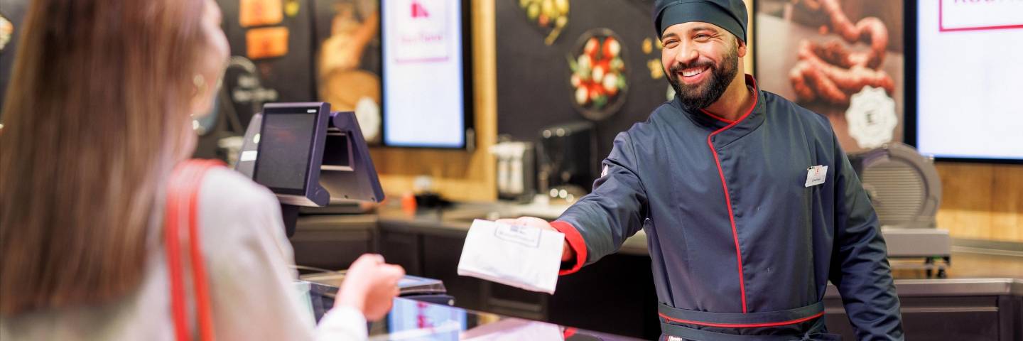 An der Bedientheke einer Kaufland-Filiale: Mitarbeiter in der Fleisch- und Wurstabteilung überreicht der Kundin ihre Bestellung.
