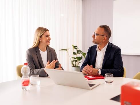 Kandidatin mit Kaufland-Mitarbeiter in einem Konferenzraum der Zentrale beim Bewerbungsgespräch. Auf dem Tisch steht ein aufgeklappter Laptop.